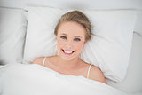 Natural smiling blonde lying in bed