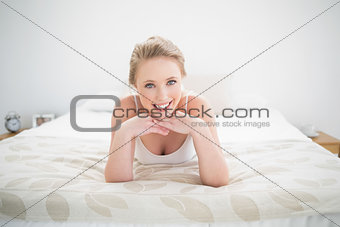 Smiling natural blonde lying on bed