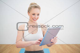 Smiling sporty blonde using tablet