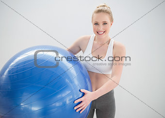 Cheerful sporty blonde holding exercise ball