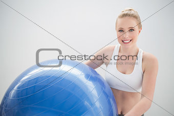 Smiling sporty blonde holding exercise ball