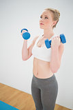 Content sporty blonde holding dumbbells