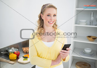 Smiling cute blonde holding smartphone