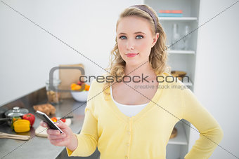 Pleased cute blonde holding smartphone