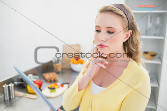 Thoughtful cute blonde using tablet