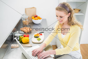 Smiling cute blonde typing on her laptop