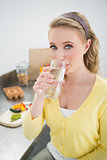 Happy cute blonde drinking a glass of water