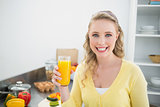 Smiling cute blonde holding a glass of orange juice