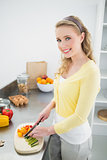 Smiling cute blonde chopping vegetables
