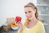 Smiling cute blonde holding a red pepper