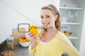 Cheerful cute blonde holding a yellow pepper