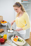 Cheerful cute blonde stirring with wooden spoon