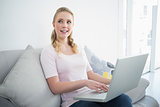 Casual pretty blonde sitting on couch using laptop