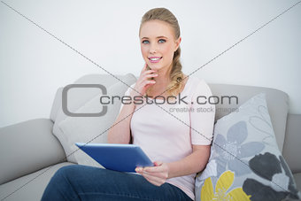 Casual cheerful blonde holding tablet
