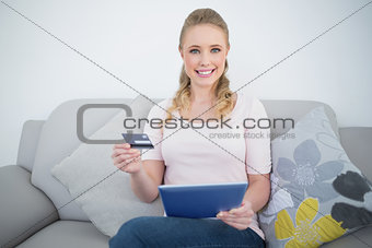 Casual cheerful blonde holding tablet and credit card