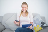 Casual cheerful blonde using tablet and credit card