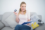 Casual excited blonde holding tablet and credit card