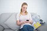 Casual smiling blonde using smartphone