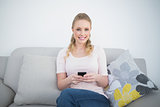 Casual smiling blonde holding smartphone