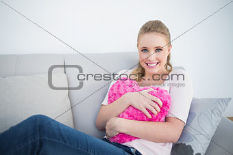 Casual smiling blonde holding heart pillow