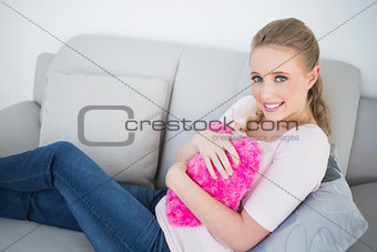 Casual happy blonde holding heart pillow