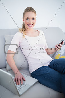 Casual cheerful blonde using smartphone and laptop
