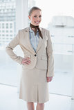 Blonde smiling businesswoman standing hand on hips