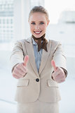 Blonde smiling businesswoman showing thumbs up