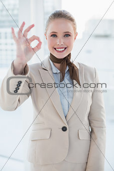 Blonde smiling businesswoman showing okay gesture