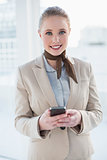 Blonde cheerful businesswoman holding smartphone