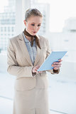 Blonde serious businesswoman looking at tablet