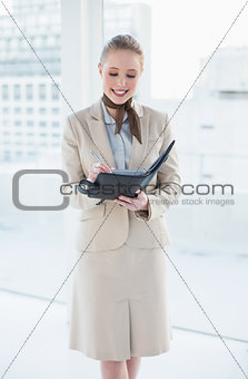 Blonde smiling businesswoman using a diary