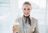 Blonde smiling businesswoman holding disposable cup