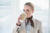 Blonde content businesswoman drinking out of disposable cup