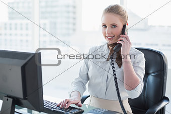 Blonde cheerful businesswoman phoning at desk