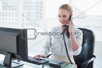 Blonde happy businesswoman phoning at desk