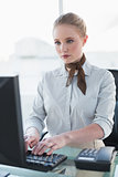 Blonde stern businesswoman working on computer