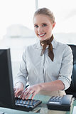 Blonde smiling businesswoman working on computer