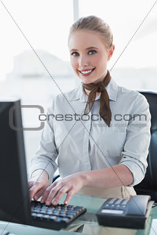 Blonde smiling businesswoman working on computer