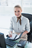 Blonde happy businesswoman writing in diary