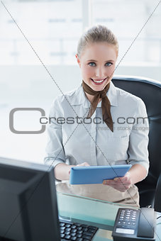 Blonde smiling businesswoman using tablet