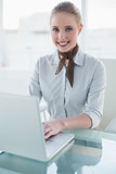 Blonde cheerful businesswoman using laptop