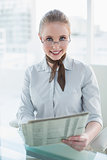 Blonde smiling businesswoman holding newspaper