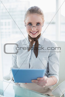 Blonde content businesswoman holding tablet