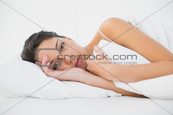 Calm casual brunette lying in her bed