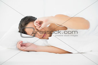 Sleepy casual brunette waking up and rubbing her eyes