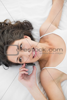 Cheerful casual brunette in white pajamas calling with her mobile phone