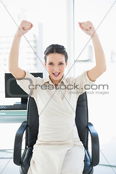 Cheering stylish brunette businesswoman raising her arms