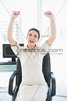 Excited stylish brunette businesswoman raising her arms