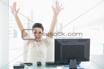 Euphoric stylish brunette businesswoman raising her arms